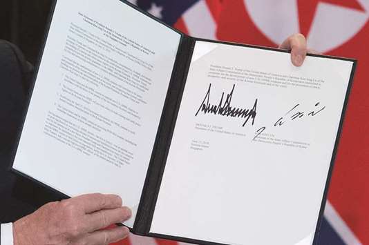 US President Donald Trump holds up a document signed by him and North Koreau2019s leader Kim Jong-un following a signing ceremony during their historic US-North Korea summit.