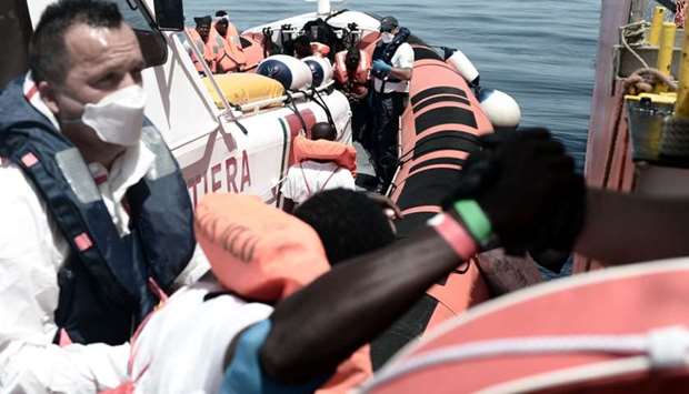 Rescued migrants and MSF personnel onboard an Italian coastguard ship following their transfer from the French NGO's ship Aquarius