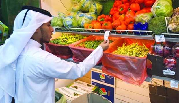 An MEC inspector checks prices at a fruits and vegetables shop.