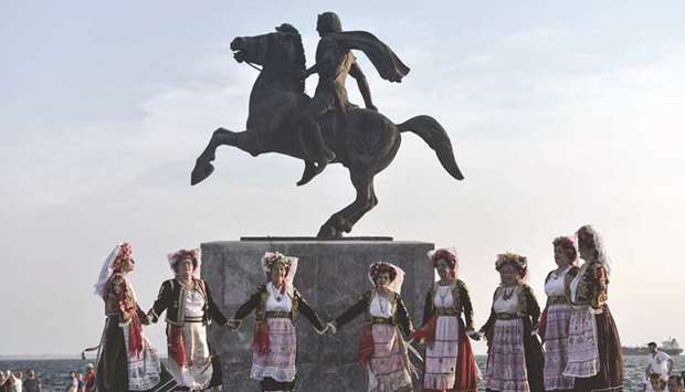 Dancers wearing traditional costumes perform in front of the statue of Alexander III of Macedon, commonly known as Alexander the Great, in Thessaloniki.