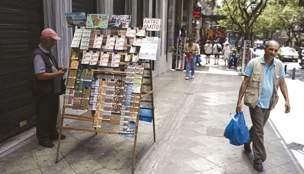A pedestrian passes a street vendor selling lottery tickets on a sidewalk in Athens. Greece is due to exit its latest bailout programme in August and will then have to rely on financial markets to cover its borrowing needs.