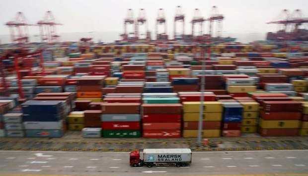 A container truck moves past containers at the Yangshan Deep Water Port in Shanghai