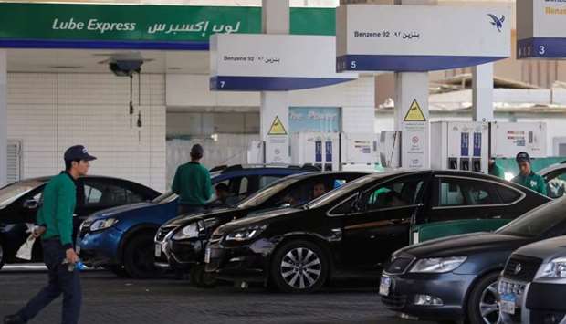 Workers fill cars as people queue and wait in their cars at a petrol stations after an increase in fuel prices in Cairo, Egypt
