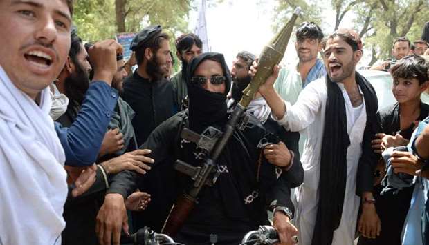 An Afghan Taliban militants carries a rocket-propelled as he looks on with residents as they took to the street to celebrate ceasefire on the second day of Eid in the outskirts of Jalalabad