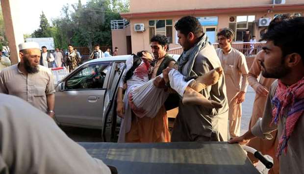 Men carry an injured man in a hospital after a car bomb, Jalalabad city