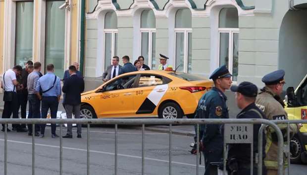 Investigators and members of emergencies services gather near a damaged taxi, which ran into a crowd of people, is evacuated in central Moscow.