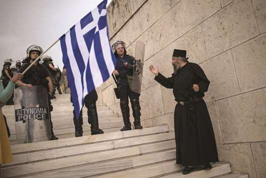 A priest argues with police officers during the demonstration in Athens yesterday against the agreement reached to resolve a 27-year name row with Macedonia.