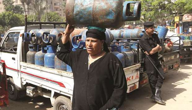 A woman carries a cooking gas cylinder at a selling depot in Cairo (file). The oil ministry raised the price for a canister of gas for Egyptian households to 50 pounds from 30, while a bottle of gas for commercial purposes was raised to 100 pounds from 60.