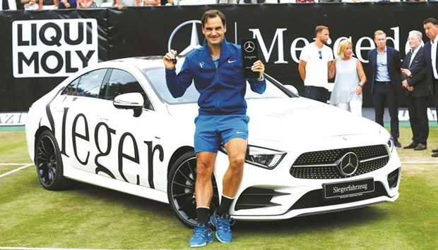 Switzerlandu2019s Roger Federer poses with the trophy in front of the winneru2019s car, a Mercedes-Benz E450, after he defeated Canadau2019s Milos Raonic in the final of the ATP Mercedes Cup in Stuttgart yesterday. (Reuters)