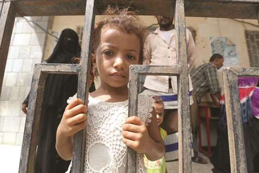 A girl stands behind a fence at a school to which she and her family have been evacuated from a village near Hodeidah airport.