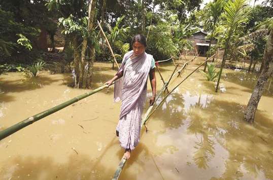 A villager uses a makeshift bamboo bridge to cross a flooded area in the Nagaon district of Assam.
