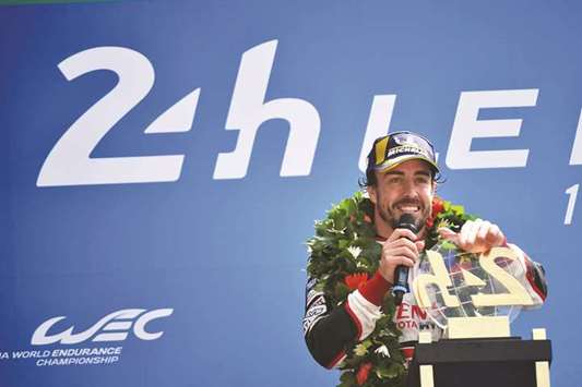 Spainu2019s driver Fernando Alonso celebrates on the podium with his trophy after winning the 86th Le Mans 24-hours endurance race, at the Circuit de la Sarthe in Le Mans, France. (AFP)