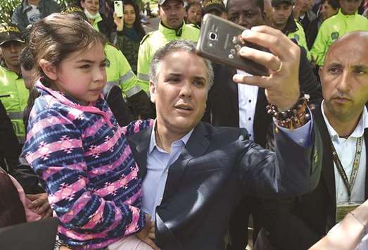 Colombia President-elect Ivan Duque takes a selfie with a girl after casting his vote in the presidential runoff election in Bogota on Sunday.