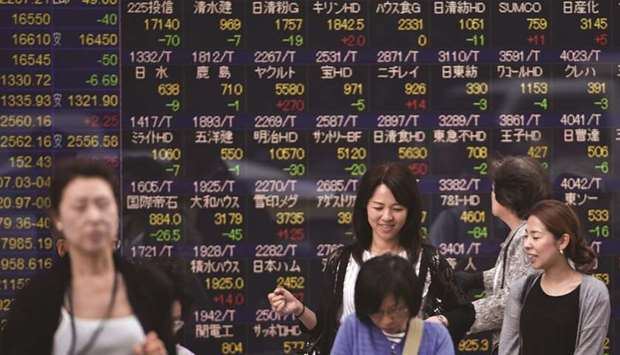 Pedestrians walk past an electronic quotation board in Tokyo. The Nikkei 225 closed down 0.8% to 22,680.33 points yesterday.