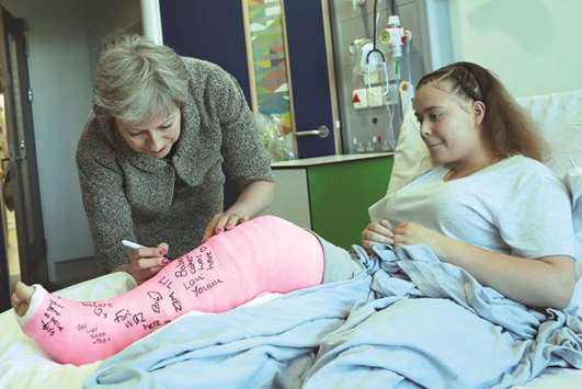 May signs the cast of patient Jade Myers, 15, who broke her leg falling off a wall, during her visit to the Royal Free Hospital in London.