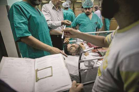 THE DREAD: Doctors prepare hospital paperwork before starting a life-saving amputation surgery for Baha Abu Ayash, at Shifa Hospital in Gaza City, Gaza Strip, on May 21.