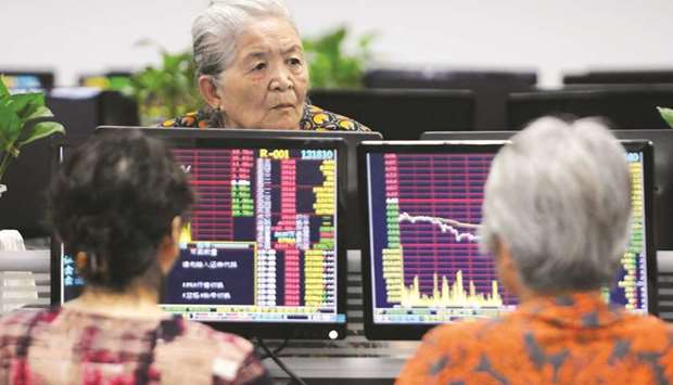 Investors monitor stock prices at a securities company in Jiujiang in Chinau2019s central Jiangxi province yesterday. Chinau2019s benchmark equity gauge sank almost 5% at one point and by the close, the escalating tensions with the US had sent 1,023 stocks down by the daily 10% limit, or more than one in four.