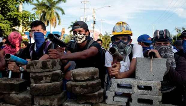 Demonstrators stand behind a barricade during clashes with riot police during a protest against Nicaragua's President Daniel Ortega's government in Managua.
