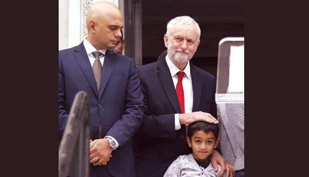 Home Secretary Sajid Javid (left) looks on as Corbyn embraces the grandson of Makram Ali on the steps of Islington Town Hall on the anniversary of the Finsbury park attack in London yesterday.