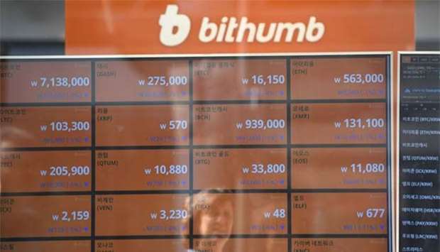 A woman is reflected on a screen showing exchange rates of cryptocurrencies at Bithumb virtual currency exchange in Seoul on Wednesday.