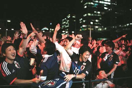 Japanese football fans celebrate Japanu2019s victory over Colombia at a fan zone in Tokyo yesterday.