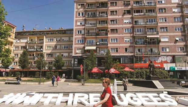 A pedestrian walks past block letters reading u201c#withrefugeesu201d yesterday on World Refugee Day in downtown Pristina.