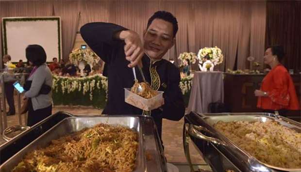 A waiter packing uneaten food for distribution through the programme ,A Blessing to Share,, after a wedding at a hotel in Jakarta.