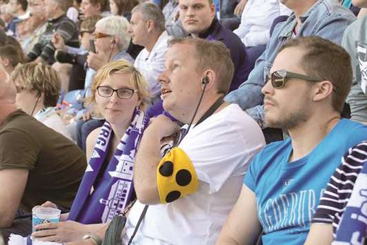 ENJOYING: A blind football fan listens to commentary provided by his club Magdeburg. He also wears a symbol to show that he is visually impaired.