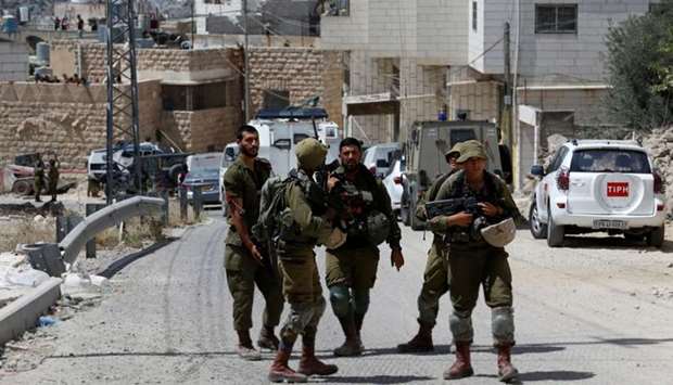 Israeli soldiers stand at the scene of alleged car ramming attack, in Hebron in the occupied West Bank