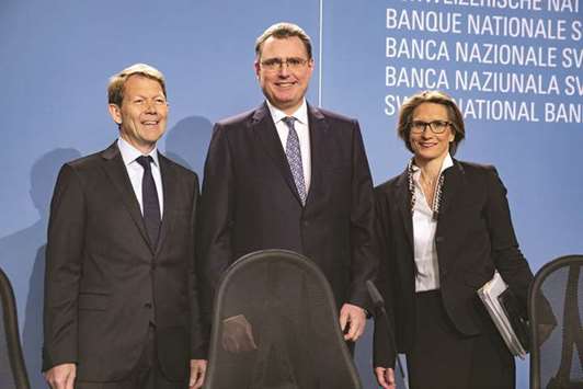 Fritz Zurbruegg, vice-president of the Swiss National Bank (left), Thomas Jordan, SNB president (centre), and Andrea Maechler, member of the governing board of the SNB, pose for photographers following the banku2019s rate announcement news conference in Bern yesterday. Jordan said after the announcement that some of the francu2019s recent swings have been u201csubstantial,u201d emphasising his heightened caution.