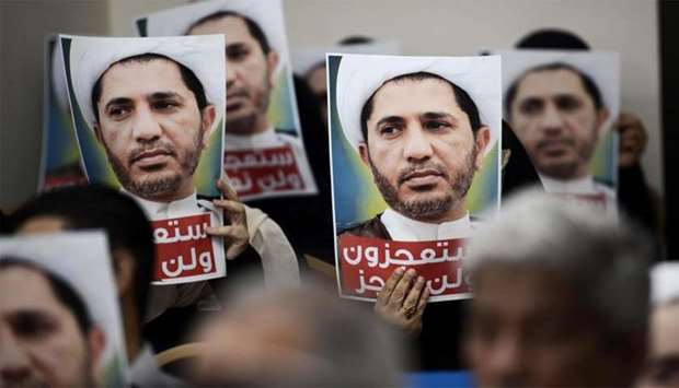 Bahraini men hold placards bearing the portrait of Sheikh Ali Salman in the village of Zinj on the outskirts of the capital Manama
