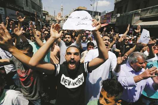 Protesters chant slogans during a protest against the new income tax law and high fuel prices, in Amman, yesterday. The banner reads in Arabic u201cwe do not have money.u201d