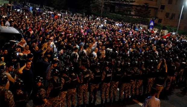 Demonstrators stand face to face with riot police during a protest in front of the Prime Minister's office in Amman