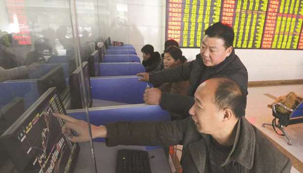 Investors talk as they look at a computer screen showing stock information at a brokerage house in Fuyang, Anhui province, China (file). Chinau2019s equity market has been recovering from its mid-2015 crash, helping power the best performance in eight years in 2017 for hedge funds investing in the region.