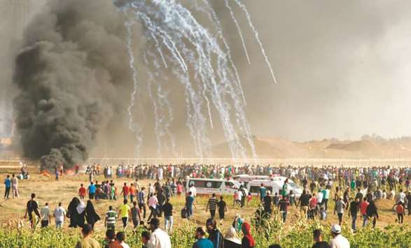 Palestinian protesters run for cover after Israeli forces launched teargas canisters during a demonstration along the border between the Gaza strip and Israel, east of Gaza city, yesterday.