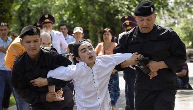 Police officers detain an opposition supporter attempting to stage a protest rally in Almaty