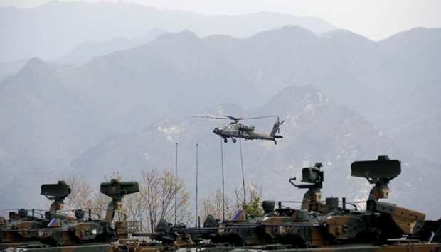 A US Army's AH-64 Apache helicopter flies over amoured vehicles, during a US-South Korea joint live-fire military exercise, at a training field, near the demilitarized zone, separating the two Koreas in Pocheon, South Korea, on April 21, 2017.