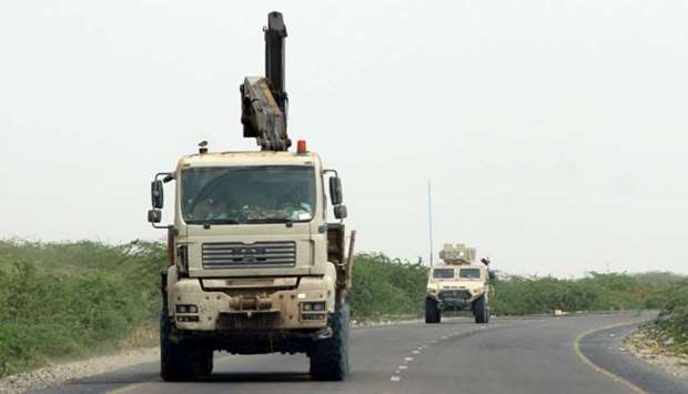 A truck crane and an armoured vehicle belonging to the Amalqa (,Giants,) Brigades, loyal to the Saudi-backed government, driving along a road during the offensive to seize the Red Sea port city of Hodeidah from Iran-backed Houthi rebels.