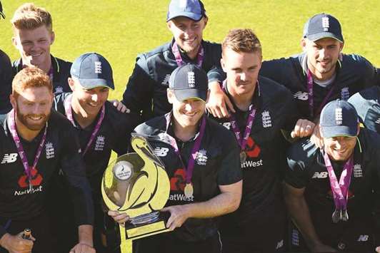 Captain Eoin Morgan holds the trophy as England team celebrate after their win in the fifth One Day International against Australia at Old Trafford cricket ground in Manchester, northwest England. (AFP)