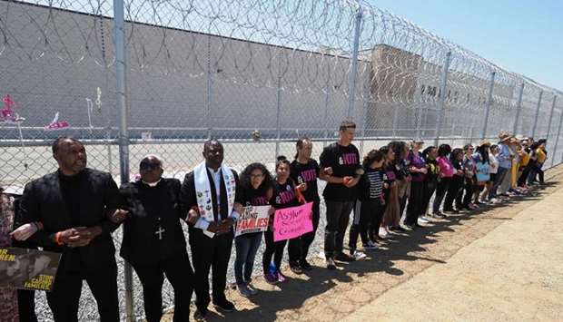 Protesters link arms after tying children's shoes and keys on the fence outside the Otay Mesa Detention Center during a demonstration against US immigration policy that separates children from parents, yesterday in San Diego, California.