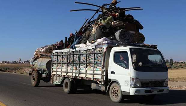 People ride on a truck loaded with belongings in Deraa countryside