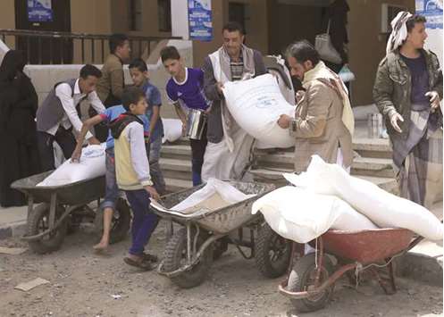 Yemenis carry sacks of food aid distributed to displaced people, who fled battles in Saada province and other war affected areas in Yemen, at a school used as shelter in Sanaa.