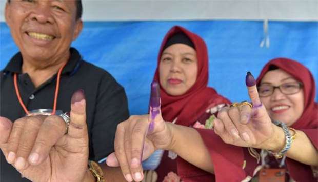 Indonesian people show their inked fingers after casting their ballots during regional elections in Tangerang, Banten on Wednesday.