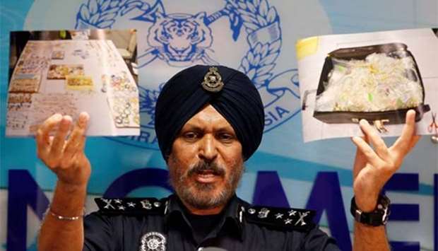Commissioner Amar Singh, Malaysia's Federal Commercial Crime Investigation Department director, displays photos of items seized during a raid at a news conference in Kuala Lumpur on Wednesday.