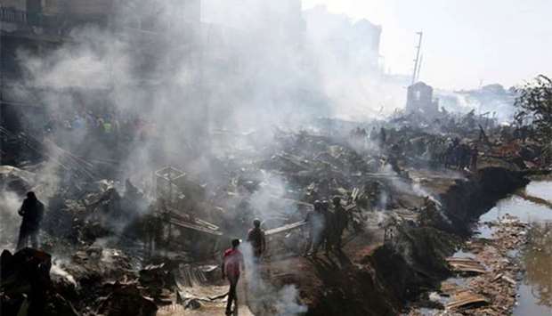 Rescue workers walk at the smouldering scene of fire that gutted down the timber dealership of the Gikomba market and nearby homes in Nairobi on Thursday.