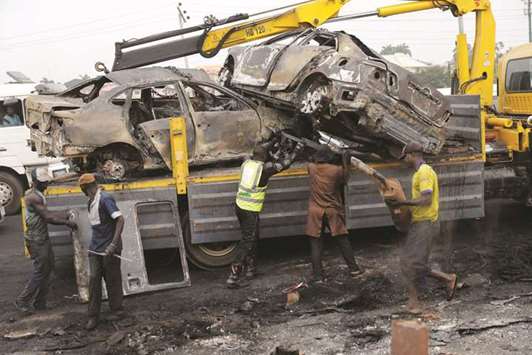 Rescue workers load burned vehicles onto a truck after a fire accident involving an oil tanker along the Lagos-Ibadan expressway in the Ojodu axis of Lagos, Nigeria yesterday.