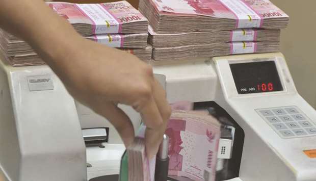 An employee counts Indonesian rupiah banknotes at a money changeru2019s office in Jakarta (file). The rupiah and ringgit bonds are vulnerable due to the debt burdens of their governments, according to Guillermo Osses, head of emerging-market debt strategies at Man GLG.