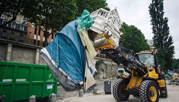 A worker usew an excavator to clean up a migrants' makeshift camp along the Canal de Saint-Martin at Quai de Valmy in Paris, following its evacuation.