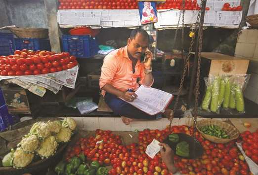 A vendor speaks on his mobile phone as he maintains his ledger book at a stall selling vegetables in Mumbai yesterday. Vegetable prices jumped as much as 10% in major cities, including Mumbai and Delhi, as a four-day-old strike by millions of farmers curtailed supplies.