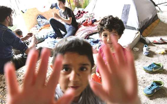 Children gesture at the camera at a makeshift migrant centre in Bihac.